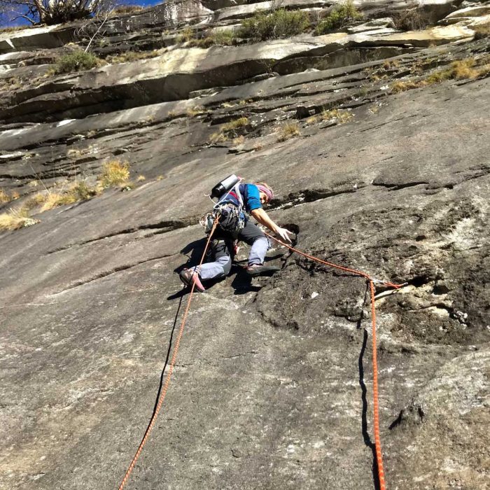 Arrampicatore fotografato dal basso su parete rocciosa